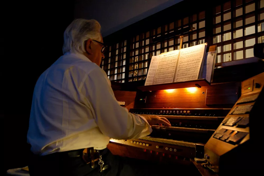 Organista przy kontuarze organów piszczałkowych, oświetlony pulpit z nutami